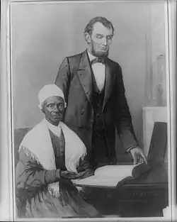 Photographie noir et blanc d'une femme noire assise qui montre de la main une bible et un homme blanc, le président des États-Unis, debout derrière elle