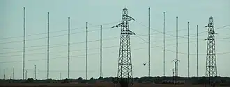Plusieurs mats d'antenne de grandes taille rapprochées les unes des autres à l'horizon.