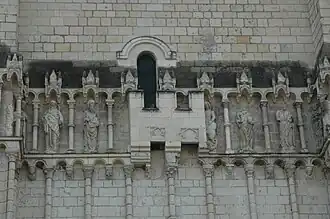 Photographie en couleurs d'une petite fortification cachant une partie des sculptures extérieures d'une église.