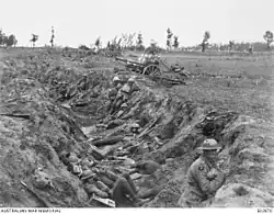 Une photographie en noir et blanc d'une tranchée dans laquelle se trouvent des troupes.