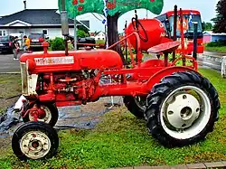 Un tracteur rouge à l'entrée d'un verger.