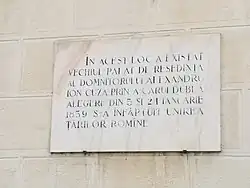 Plaque commémorative dans la cour du palais royal de Bucarest, façade sud. « En ce lieu se dressait le palais du prince souverain Alexandru Ioan Cuza, dont la double élection des 5 et 24 janvier 1859 mena à l'union des principautés roumaines. »