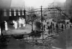 Photo noir et blanc d'un groupe de pompiers en train de projeter de l'eau sur un immeuble en feu.