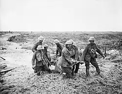 Description de l'image A team of stretcher bearers struggle through deep mud to carry a wounded man to safety near Boesinghe on 1 August 1917 during the Third Battle of Ypres. Q5935.jpg.