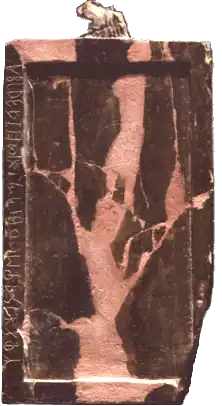 Tablette rectangulaire de petite dimension, de couleur rosée et marron, avec des symboles écrits verticalement sur le côté gauche.