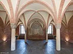 Photographie couleur d'une salle voutée en ogives de briques.