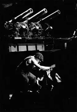 Homme caucasien sur scène devant la foule (photo en noir et blanc).