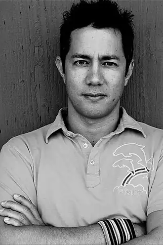 Photographie en noir et blanc d'un homme croisant les bras.