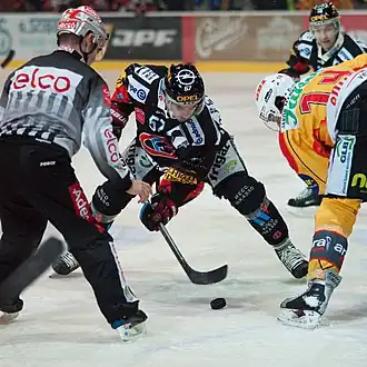 Photographie couleur de Hasani, à l'engagement face à un joueur du SC Langnau Tigers