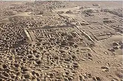 Photographie aérienne en couleurs de ruines dans le désert.