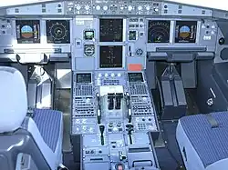 Photo rapprochée prise au centre d'un poste de pilotage, constitué de multiples cadrans, boutons et leviers.