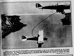 photo dans un magazine ancien. Deux biplans en vol, reliés par un tuyau recourbé.