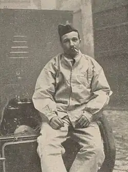 Photographie d'un homme fumant une cigarette assis sur une table.