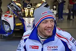 Photo d'un homme souriant, portant un bonnet gris et une combinaison de course