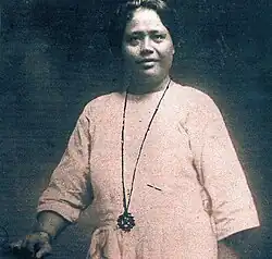 Photographie Aloisia Brial une femme brune vêtue d'une robe rose et portant un collier.