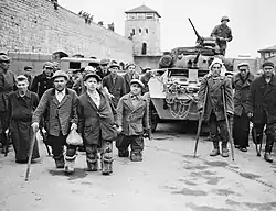 À Mauthausen, prisonniers russes et polonais infirmes après des expérimentations médicales au camp, devant un véhicule de la onzième division blindée de la troisième armée américaine qui a libéré le camp.
