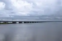 Photographie depuis une rive d'une partie d'un pont surbaissé enjambant une étendue d'eau.
