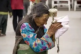 Pèlerine tibétaine avec un moulin à prières et un mâlâ lors du pèlerinage du Barkhor à Lhassa (Tibet).