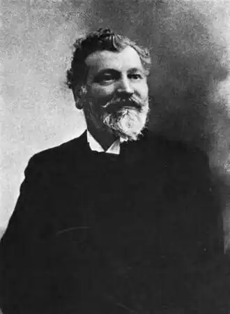 Portrait noir et blanc d'un homme barbu souriant.