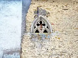 Photographie montrant un mur conservé de l'ancienne abbaye, avec sa fenêtre gothique.