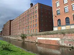 Photoraphie. Manufactures en brique« La masse rectangulaire de grandes usines aux multiples fenêtres… » Ancoats'Mills (Murray's Mills aujourd'huiMrs Gaskell amenait ses visiteurs aux Murray's Mills (dans le quartier d'Ancoats, le long du Canal Rochdale), pour leur montrer tout le processus de la fabrication des cotonnades.).
