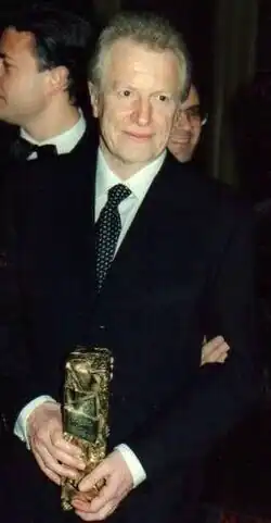 Homme blond tenant un prix.