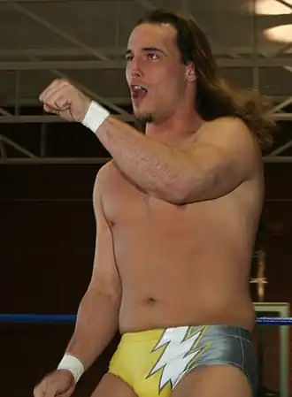 Un catcheur brun aux cheveux long portant un slip jaune.