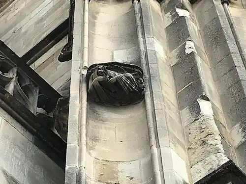 Entre deux niches vides, une sculpture d'un ange soufflant dans un instrument à vent.