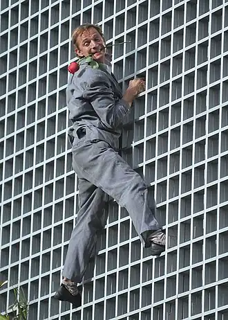Antoine le Menestrel grimpant sur un mur et portant une rose dans sa bouche