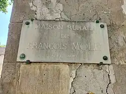 Plaque à gauche de la porte d'entrée.