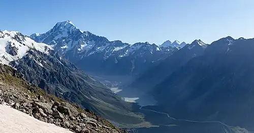 Une montagne pointue et neigeuse couronne une vaste vallée.