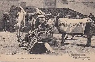 Carte postale en noir et blanc d'un homme et d'une femme, accompagnés d'un âne et d'une vache.