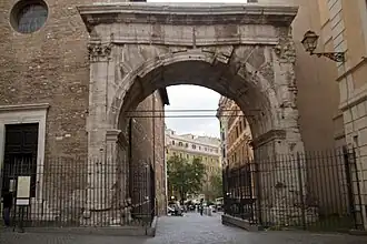 Photographie en couleurs d'un arc de triomphe enjambant une rue entre deux autres bâtiments.