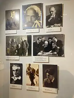 Mur couvert de portraits photographiques d'hommes en noir et blanc.