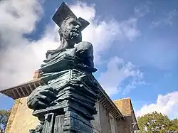Buste de Victor Hugo avec un livre ouvert sur la tête, au dessus de tous les livres écrits par l'auteur, oeuvre monumentale en bronze