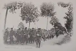 Photo noir et blanc d'une colonne de fantassins marchant sur une route.