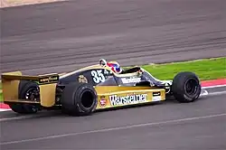 Photo d'une monoplace noire et or en piste