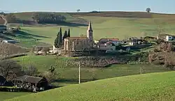 Photo de l'église de l'Assomption : une église à nef unique à proximité de quelques maisons au milieu des champs