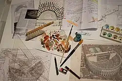 Photographie de divers outils d'aquarelliste : palette, peinceaux, brosses, papier à dessin.