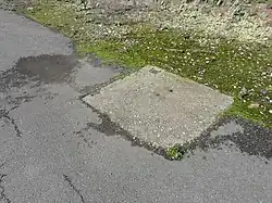 La tête de puits matérialisée, sans plaque d'égout.