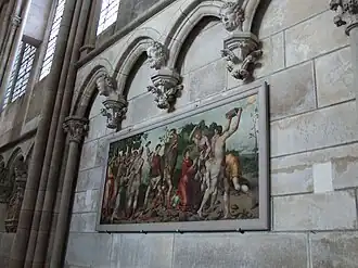 Les murs latéraux du déambulatoire sont garnis d'arcatures dotées de clés pendantes. Elles sont généralement ornées de têtes humaines. Le tableau représente la Lapidation de saint Étienne.