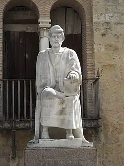 Statue en pierre claire représentant un homme assis.