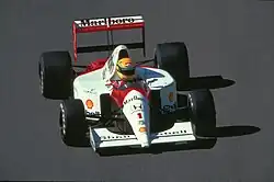 Photo d'une monoplace orange et blanche sur une piste de course.