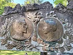 deux effigies en médaillons entourés de branches de laurier représentant à gauche un visage masculin regardant vers la droite un visage féminin.