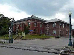 Deux bâtiments en brique derrières un chemin de fer.