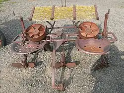 Ancien plantoir à pommes de terre, avec deux sièges-baquets en métal, table inclinée devant, et outils de calibrage derrière