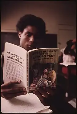 BLACK STUDENT IN A BLACK STUDIES CLASS IN A WEST SIDE CHICAGO CLASSROOM READING A BOOK ABOUT GREAT RULERS IN AFRICA'S... -