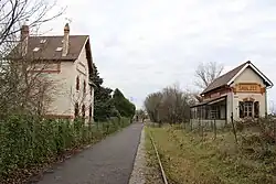 Voie bitumée, voie ferrée et bâtiments de l'ancienne gare de Saulzet