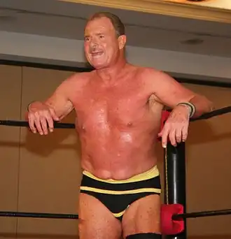 Un catcheur portant un slip noir à rayures horizontales jaune