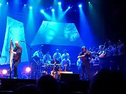 Photographie d'Alan à la harpe, entouré de son pianiste, son violoniste et du bagad de Saint-Malo